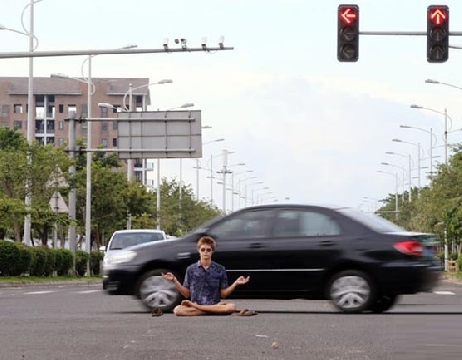 Người đàn ông cởi trần, chắp tay ngồi giữa đường